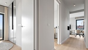 Un intérieur moderne avec un couloir menant à une salle à manger, comprenant un téléviseur à écran plat, une table à manger et des chaises.
