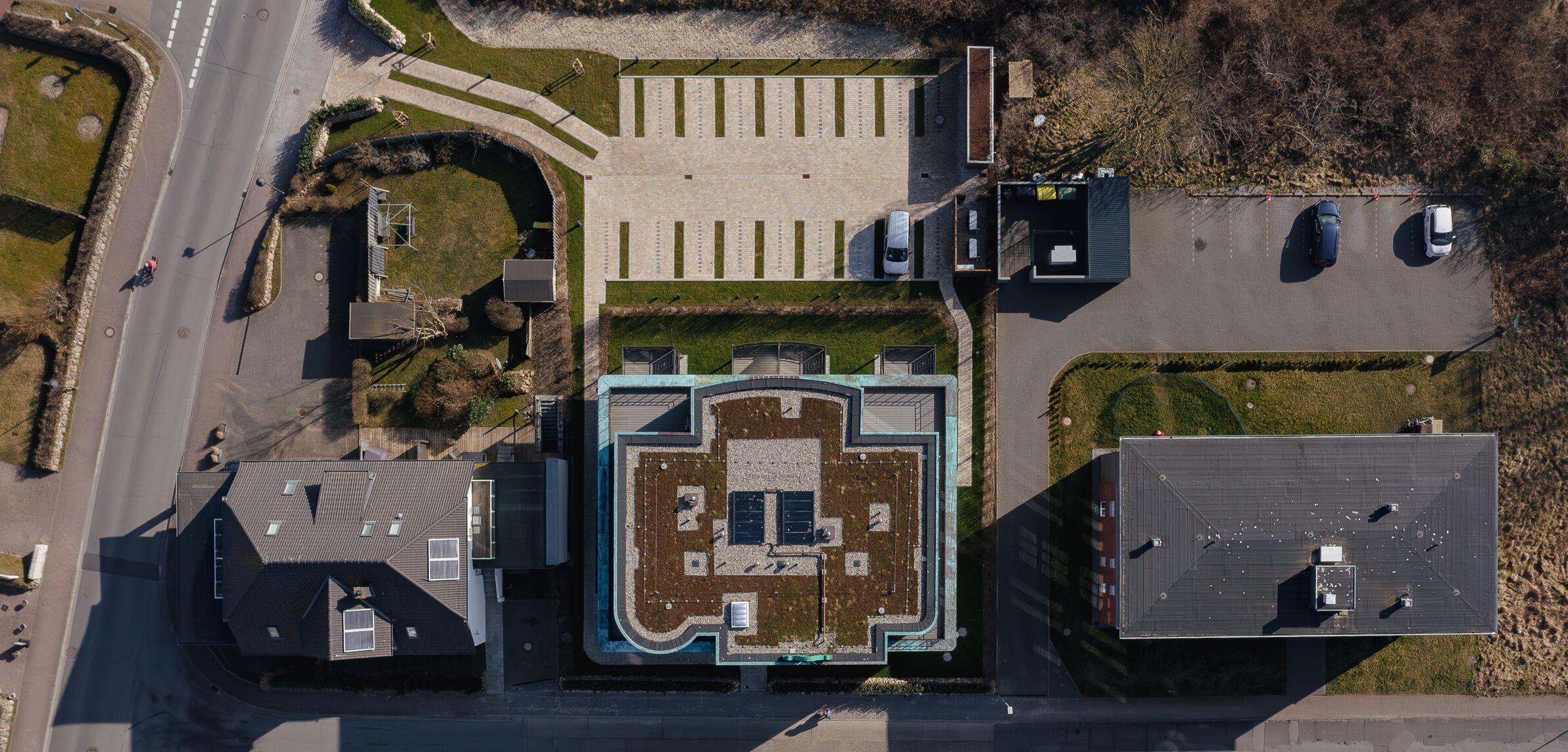 Vista aérea de un edificio con un patio central, zona de estacionamiento y estructuras adyacentes.