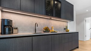 Una cucina moderna con mobili in legno scuro, una macchina da caffè integrata e un lavello in acciaio inossidabile.
