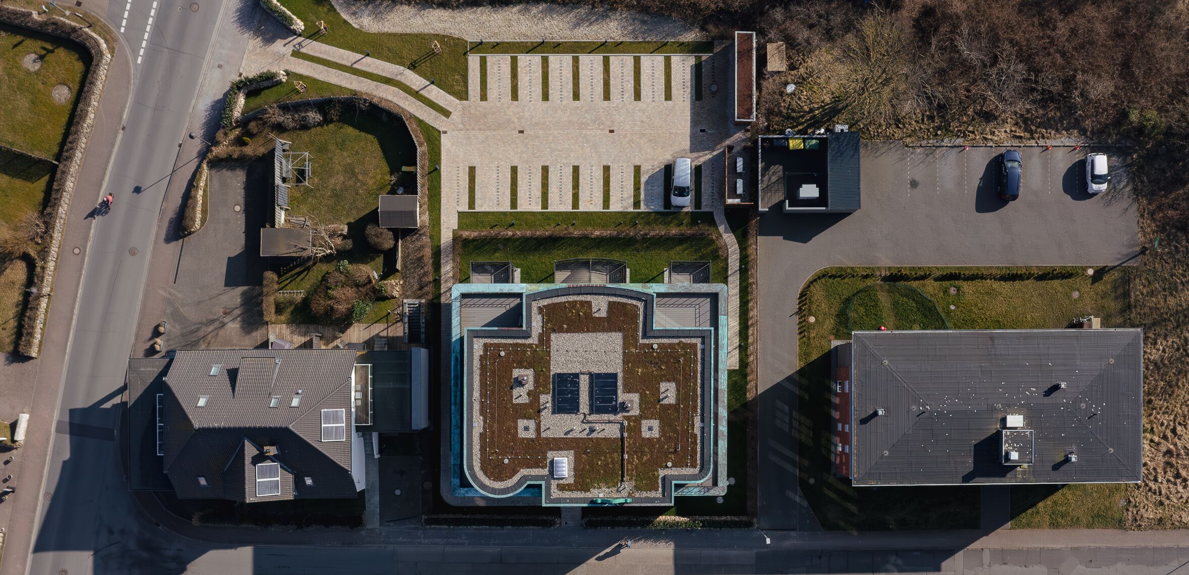 Vista aérea de un edificio con un patio central, zona de estacionamiento y estructuras adyacentes.