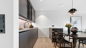 Una cocina moderna con armarios oscuros, una mesa de comedor de madera y una lámpara colgante.