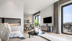A modern living room with a fireplace, a dining area, a kitchen, and a balcony with outdoor furniture. - Ocean Breeze Suite - Sea View, Wellness, Ethanol Fireplace, Infrared Cabin (List auf Sylt)