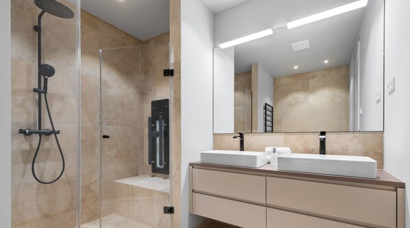A modern bathroom with a glass-enclosed shower, two sinks, and a large mirror.