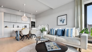 En moderne stue med sofa, sofabord og spiseplads.
