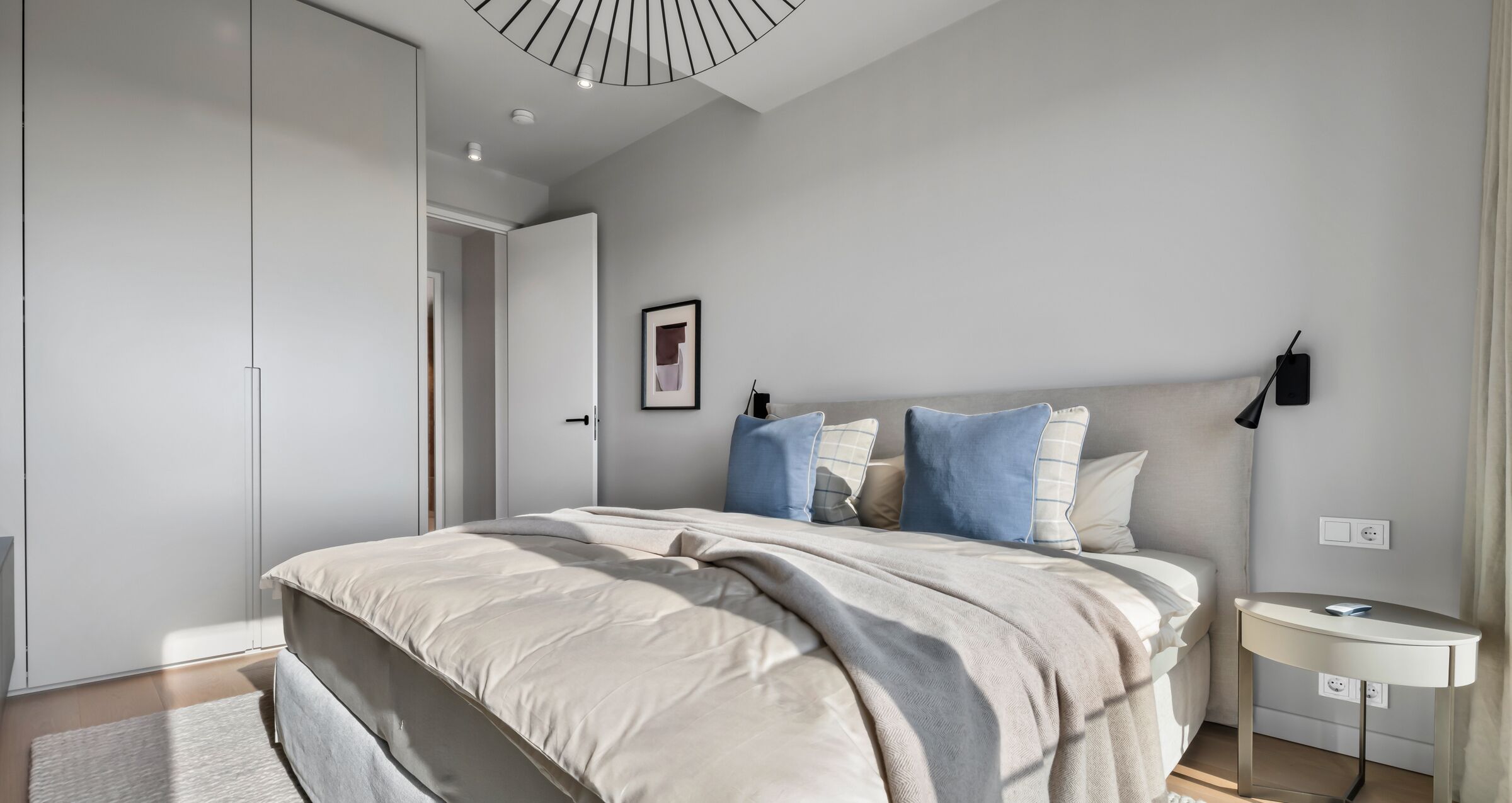 Une chambre à coucher moderne avec un grand lit, une table de chevet, une commode et un luminaire au plafond.