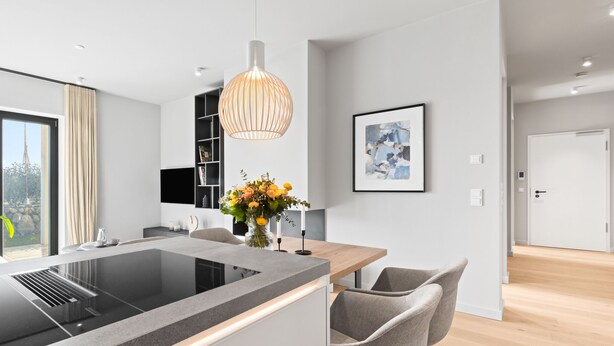 Une cuisine moderne dotée d’un îlot central, d’un luminaire suspendu et offrant une vue sur l’extérieur.