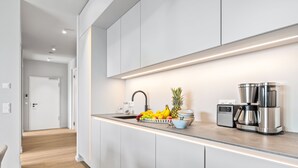 Une cuisine moderne dotée d’une machine à café en acier inoxydable, d’un panier à fruits et d’un plan de travail élégant.