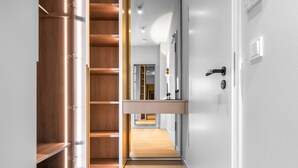 Um corredor moderno com um guarda-roupa de madeira, uma estante embutida e uma porta com fechadura.