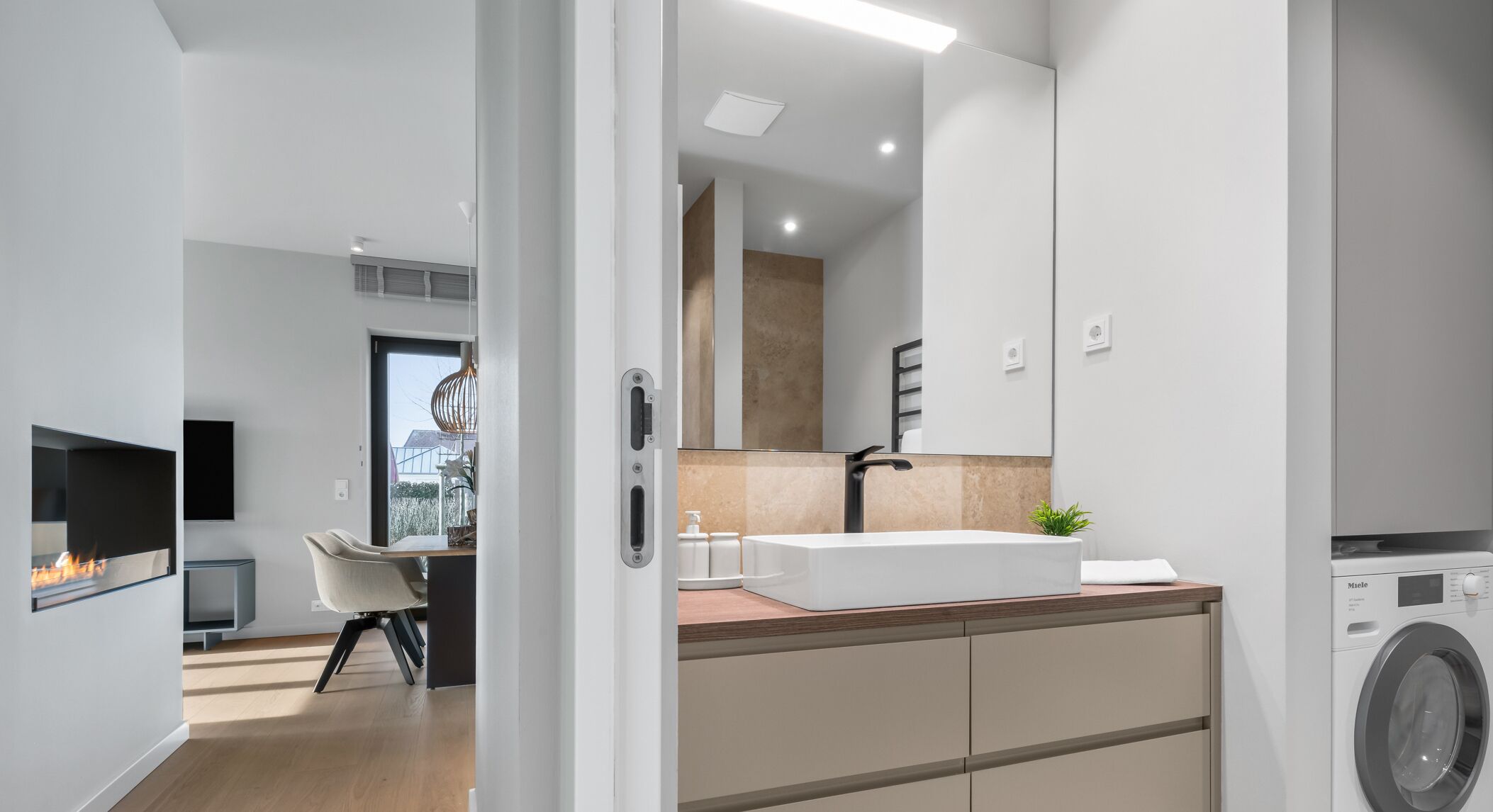Une salle de bain moderne avec un grand miroir, un lavabo et un lave-linge.