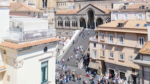 A historic town square with a prominent church, a bell tower, and a castle on a hill. - ABBRACCIO Amalfi Boutique Retreat (Amalfi)