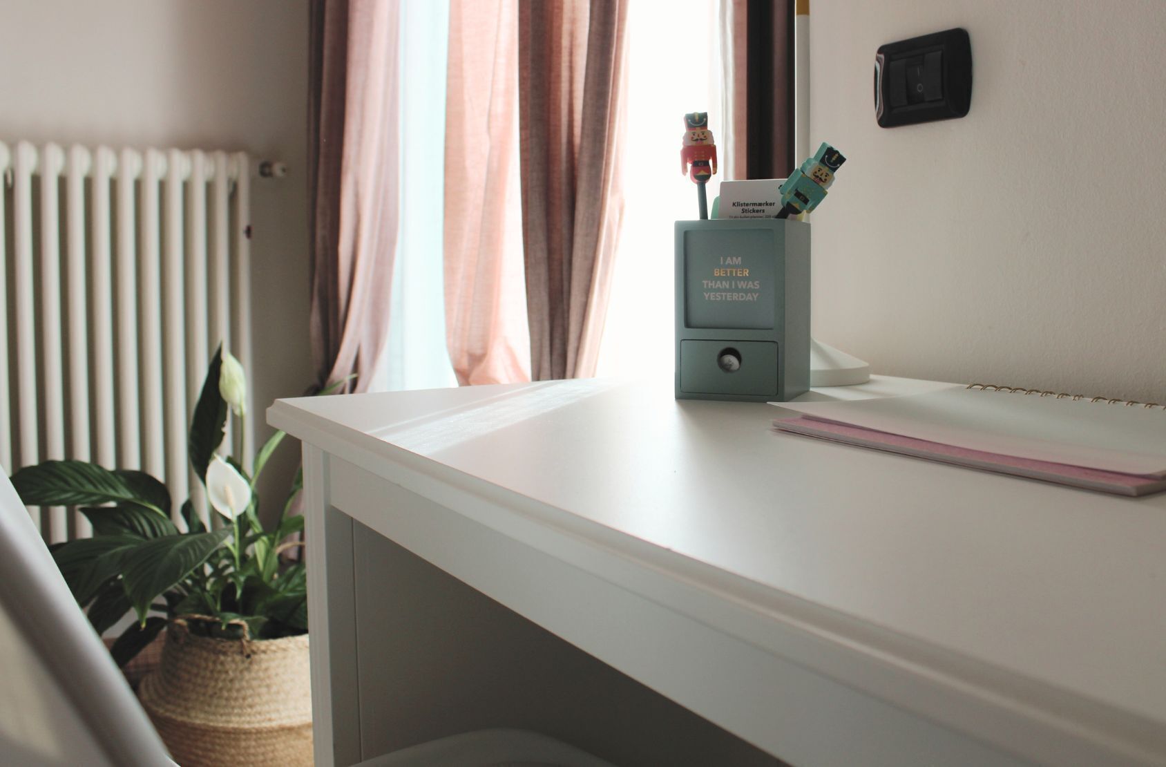 A white desk with a keyboard, a small plant, and a box of Kleisticker stickers.