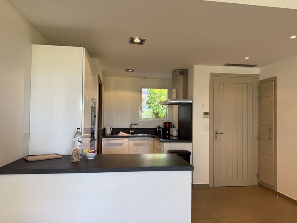 A modern kitchen with white cabinets, a black countertop, and a window providing natural light.