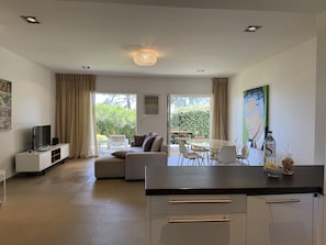 A modern kitchen with a dining area, a sofa, and a TV. - T4 Côté Plage n°6 by Pinarello Villa Services (Sainte-Lucie de Porto-Vecchio)