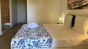 Une chambre d’hôtel avec un lit, un tableau, une lampe et une porte.