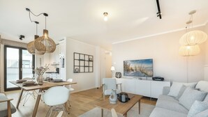 Un salon moderne avec un canapé, une table à manger et des chaises. Il y a également un coin cuisine avec des placards et une fenêtre.