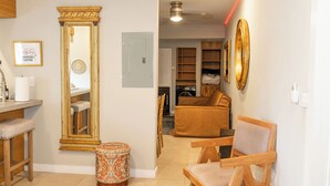 A living room with a large mirror, a sofa, a wooden chair, and a small ottoman. - Trendy Brickell 2bd/2bth Free Parking Apt 5 (Miami)