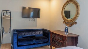 A room with a flat-screen TV mounted on the wall, a blue velvet sofa, a wooden dresser with a mirror, and a hanging clothes rack. - Trendy Brickell 2bd/2bth Free Parking Apt 5 (Miami)