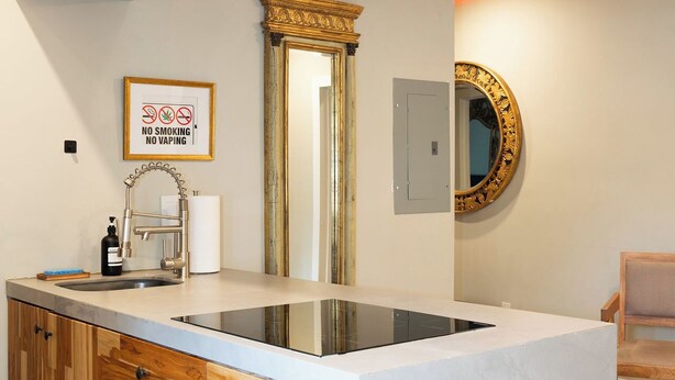 A modern kitchen with a central island, wooden cabinetry, a built-in dishwasher, and a large mirror above the sink. - Trendy Brickell 2bd/2bth Free Parking Apt 5 (Miami)