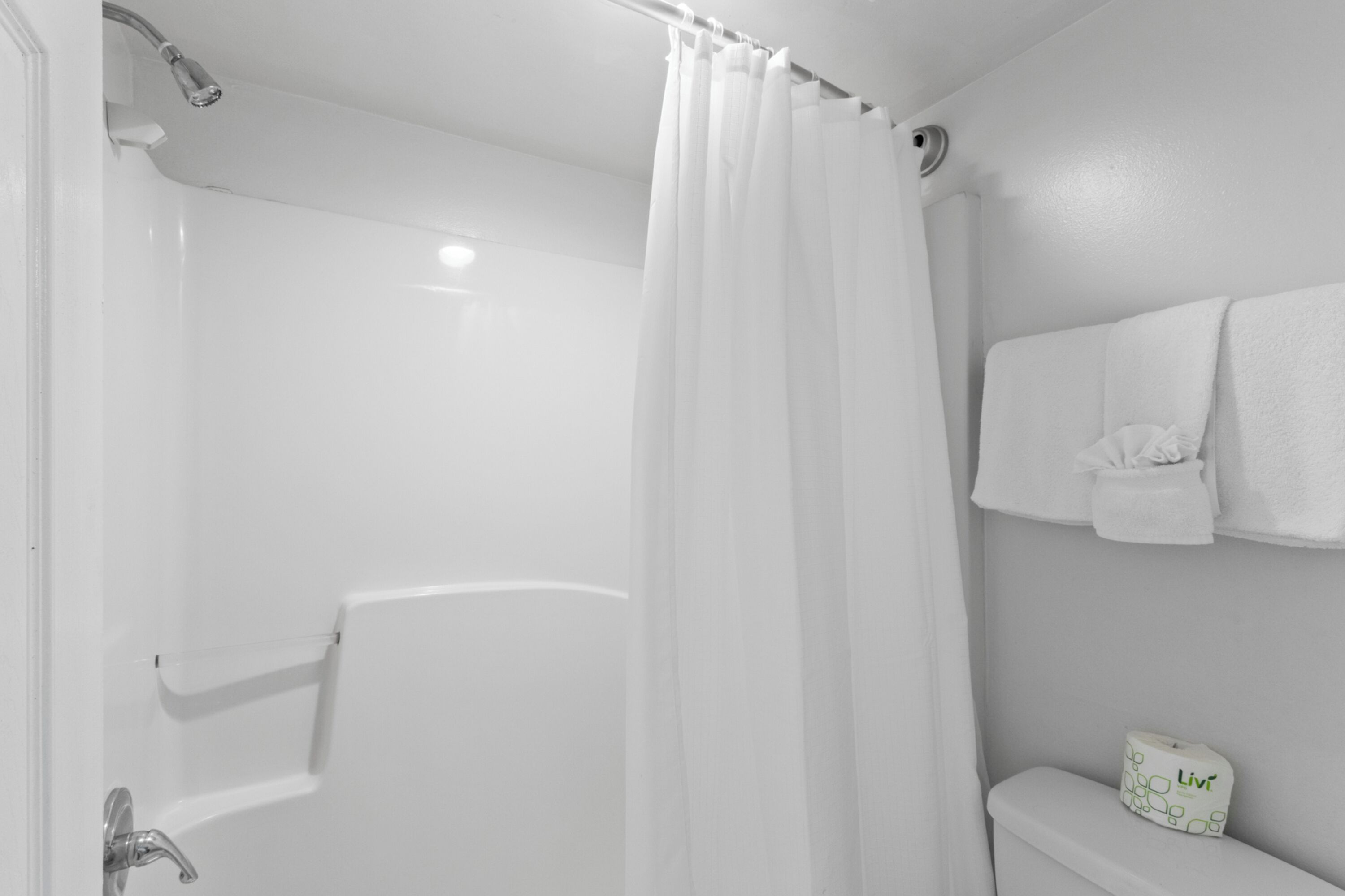 A bathroom with a bathtub, a shower curtain, a toilet, and a towel rack.