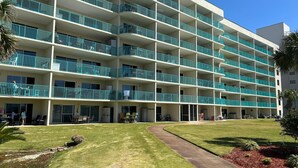 Un hotel de varios pisos con balcones, césped y un camino.