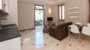 A modern apartment with a kitchen, dining area, and living room. There is a TV, a dining table with chairs, and a sofa. - Lovely apartment for 3 guests with WIFI, TV and balcony (Mergozzo)