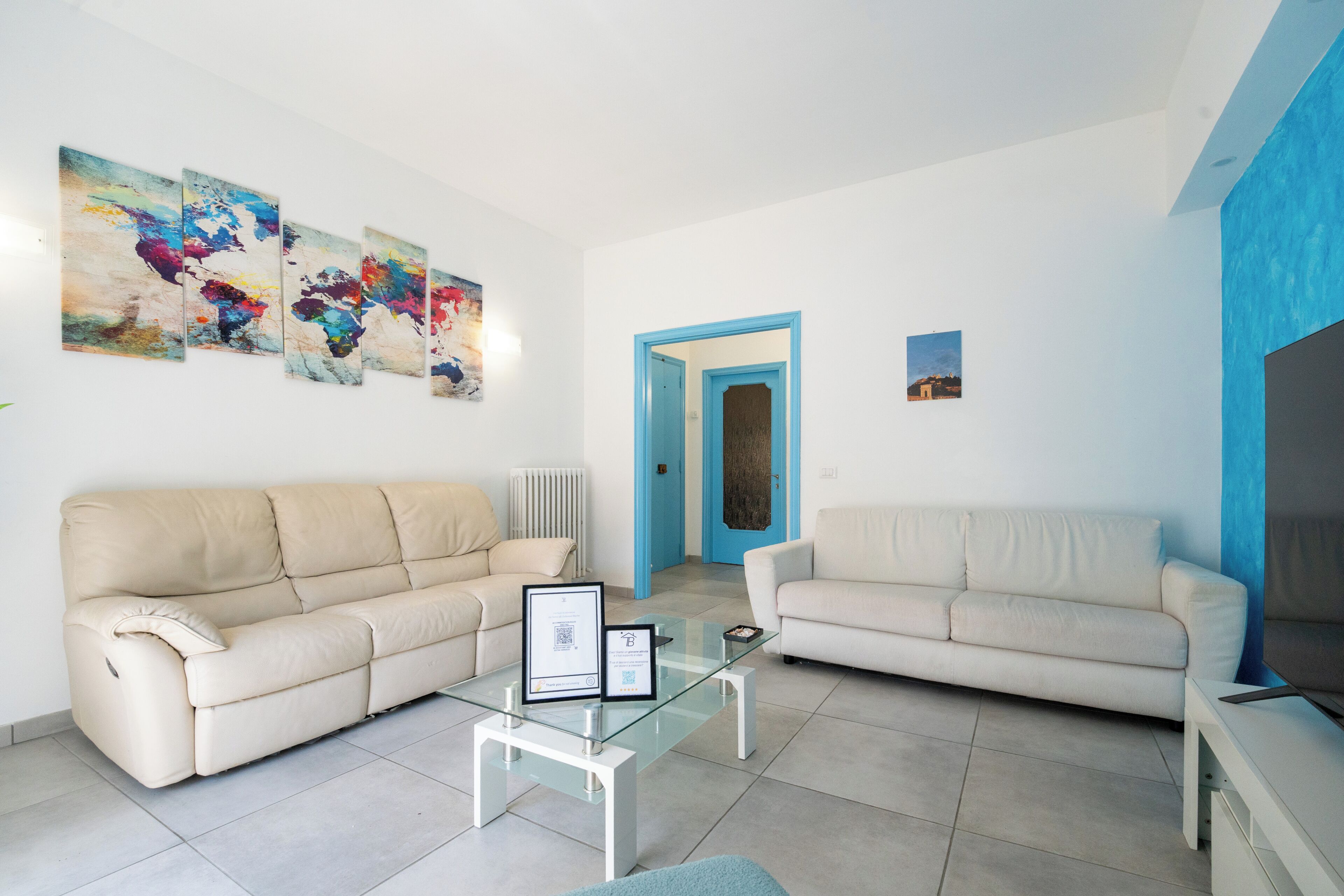 A living room with two sofas, a glass coffee table, and abstract art on the wall.