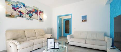 A living room with two sofas, a glass coffee table, and abstract art on the wall.