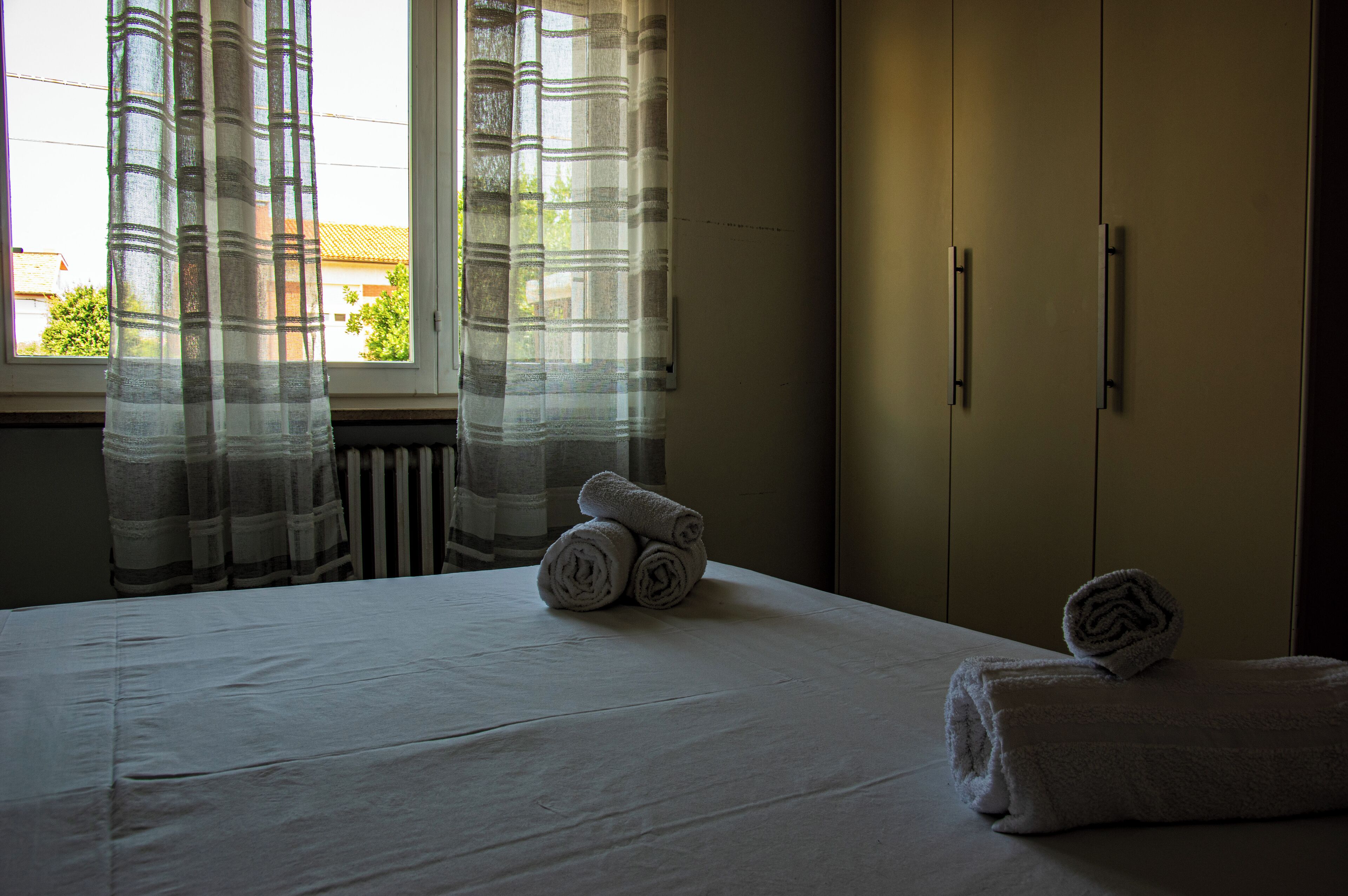 Een hotelkamer met een bed, een raam met gordijnen en een kledingkast.