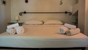 Un lit bien fait, avec des serviettes pliées, une table de chevet avec une lampe et des décorations murales.