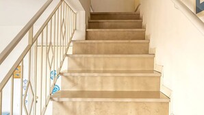 Un escalier avec des marches de couleur beige et une rampe en métal.