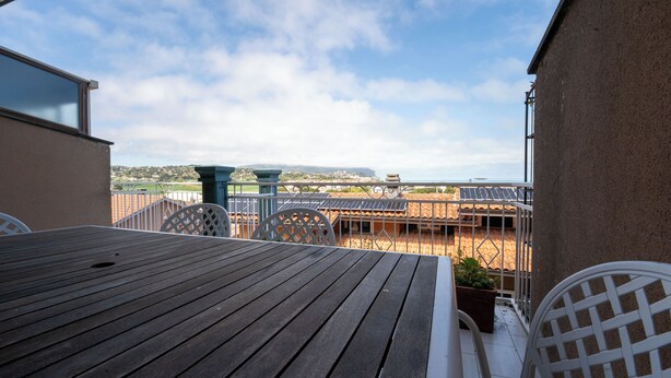 Une terrasse en bois offrant une vue sur une ville et des montagnes au loin.