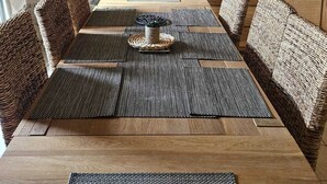 Un coin repas rustique avec un mur en pierre, des meubles en osier et un luminaire suspendu.
