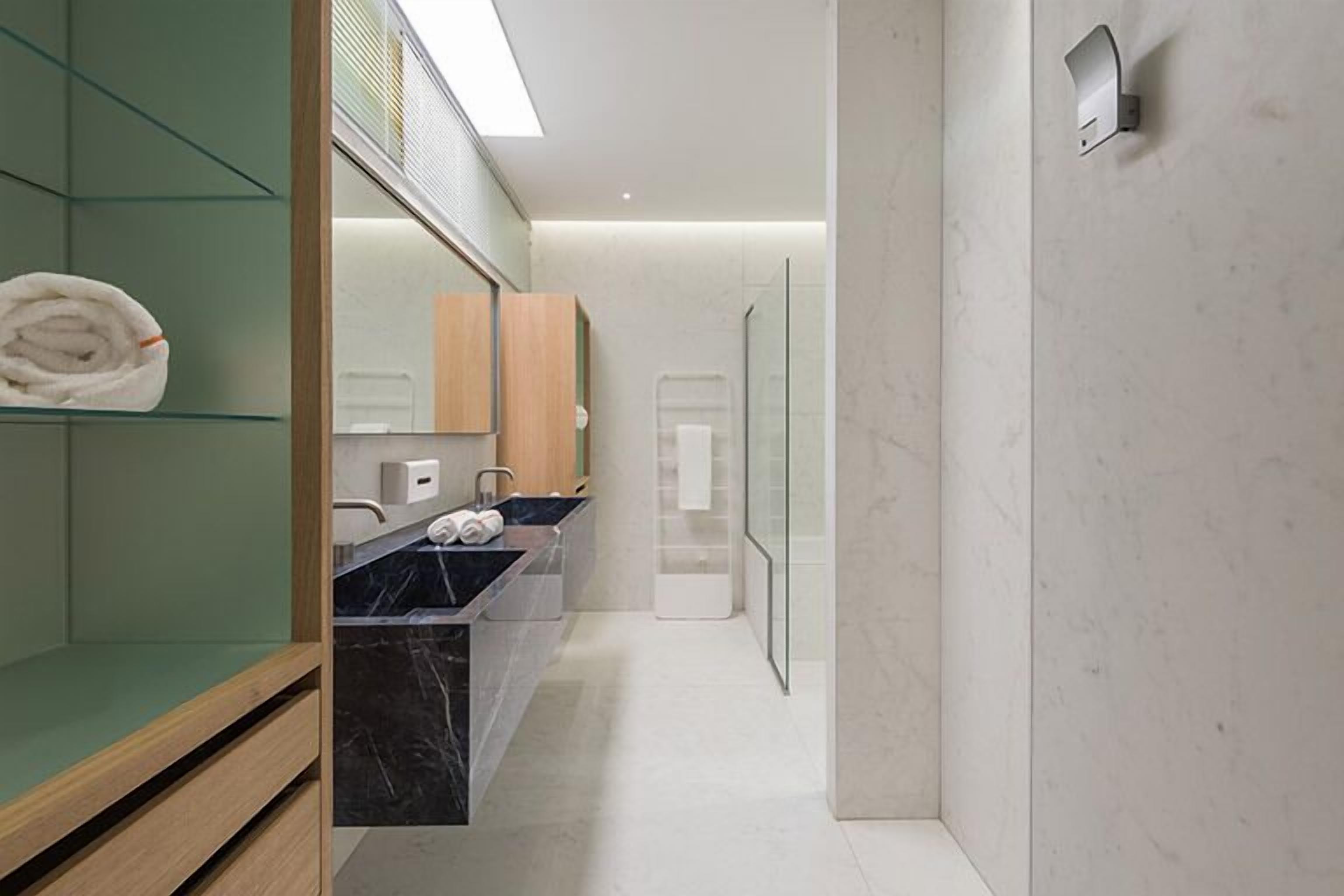 A modern bathroom with a glass shower enclosure, marble countertops, and a wooden vanity.