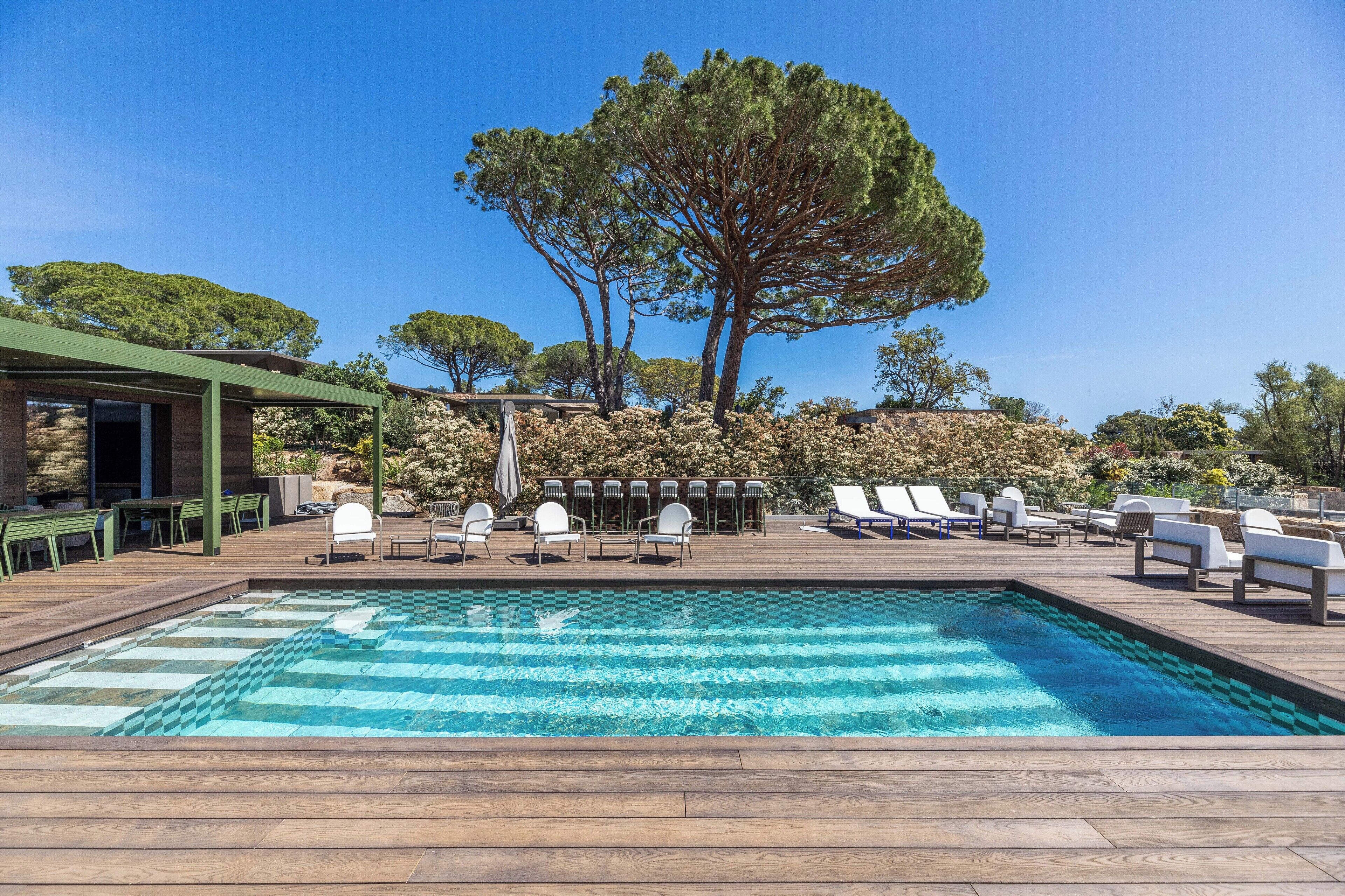 Ein Poolbereich mit Liegestühlen und einer Pergola.
