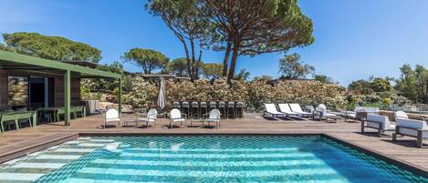 Ein Poolbereich mit Liegestühlen und einer Pergola.