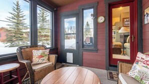 A cozy room with a wooden table, wicker chairs, and a red door. - Teton Homestead: Teton Basecamp Near Parks (Driggs)