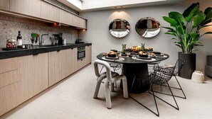 Une cuisine moderne dotée d’une lucarne, un coin repas avec une table ronde et une grande plante en pot.