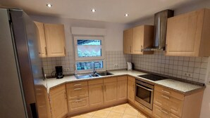 Una cucina moderna con frigorifero in acciaio inox, forno integrato e cappa aspirante.