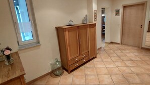Un'ampia stanza con un grande armadio in legno, pavimento piastrellato e una finestra con vista.
