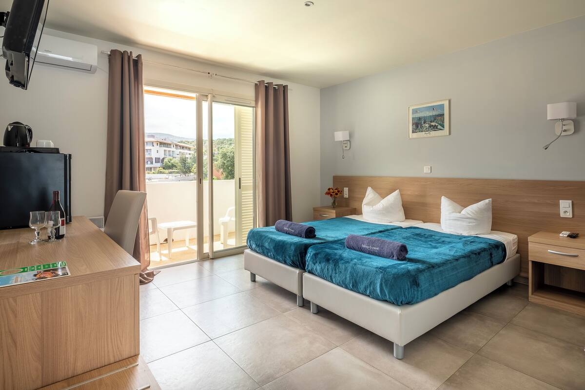 Une chambre d’hôtel avec un lit, un bureau, une télévision et une vue sur l’extérieur.