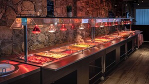 A buffet with various food options, a stone wall, and a sign with text. - Ferienhotel Maristella  (Aregno)