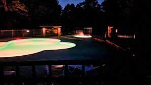 A swimming pool at night with illuminated edges and a fence surrounding it. - Rustic Wooded Branson Retreat Near Lake Taneycomo | RH230B (Branson)