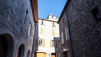 Una calle estrecha bordeada por edificios de piedra con arcos y un edificio central con una cruz en la parte superior.