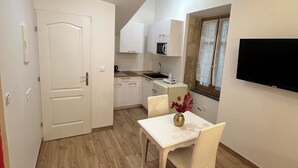 Un espacio habitable compacto con comedor, kitchenette y televisor montado en la pared.