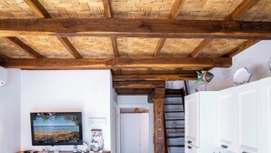 A room with a wooden ceiling, a mounted television, white cabinets, and a staircase. - Cozy Beachfront House with Stunning Sea View | Mandriola - Putzu Idu (Mandriola)