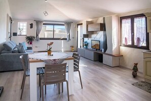 Ein moderner Wohnraum mit Essbereich, Küche und einem großen Fenster mit Vorhängen.