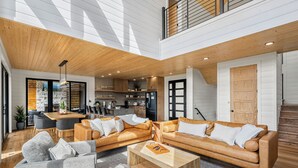 A spacious living area with a wooden ceiling, a kitchen in the background, and a staircase leading to an upper level. - MtnTopRetreat: MtnView*Pool*Theater*Games*HotTub*WiFi*Fireplaces*ResortPool (Gatlinburg)