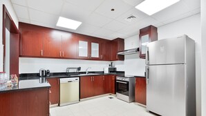 A modern kitchen with wooden cabinets, stainless steel appliances, and a dishwasher. - Savis Home – Oceanfront Serenity & Marina Views (Dubai)