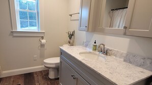 Ein Badezimmer mit Toilette, Waschbecken, Spiegel und Fenster.