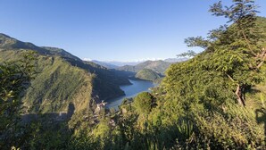 Un paisaje montañoso con un lago, vegetación densa y cielo despejado.